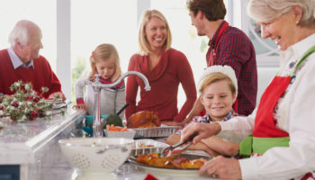 Family around the kitchen while grandmother cuts holiday food